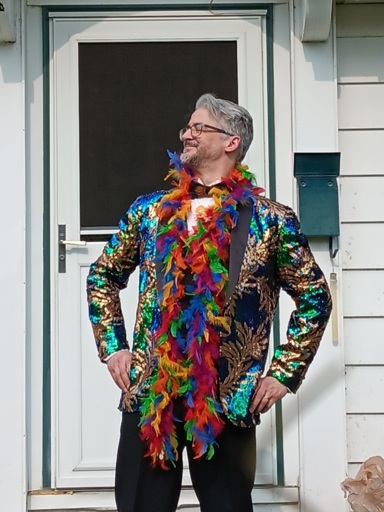man in a sequined tuxedo jacket and rainbow feathered boa